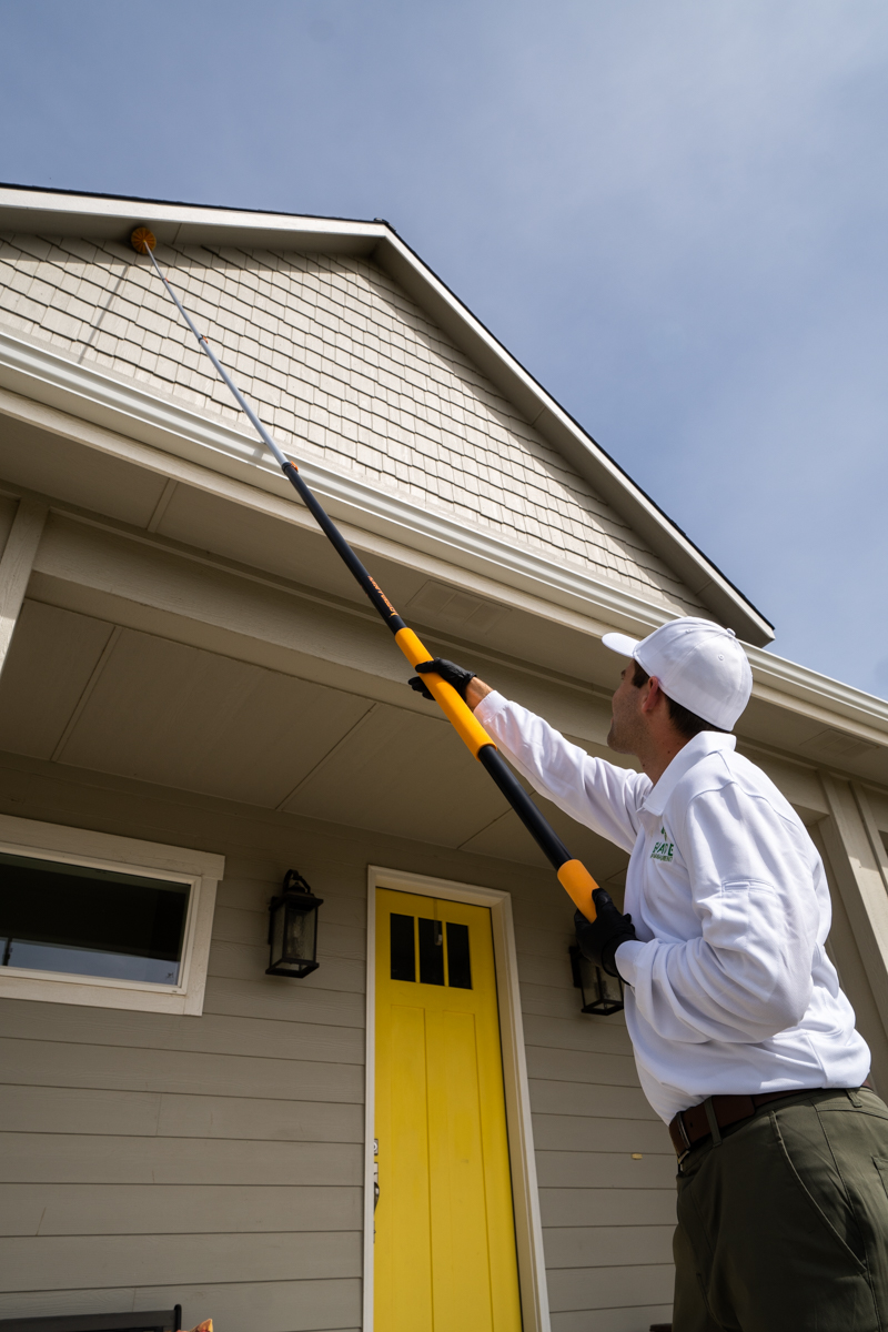 Evade Pest Management technician performing pest control treatment to exterior of home